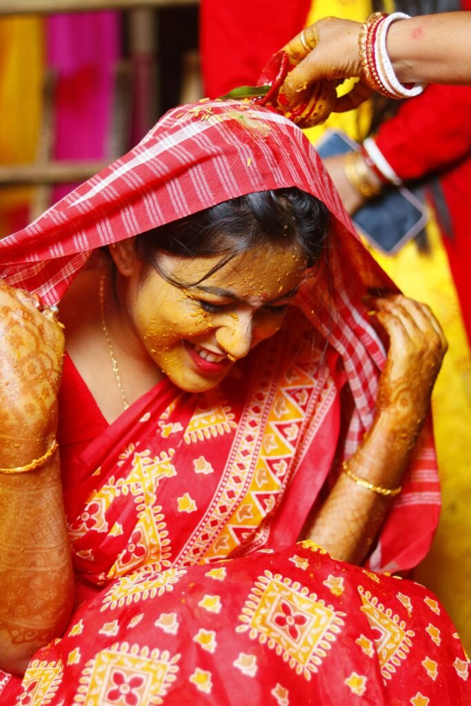 A joyful moment from a traditional Indian haldi ceremony, showcasing intricate henna designs and vibrant clothing.