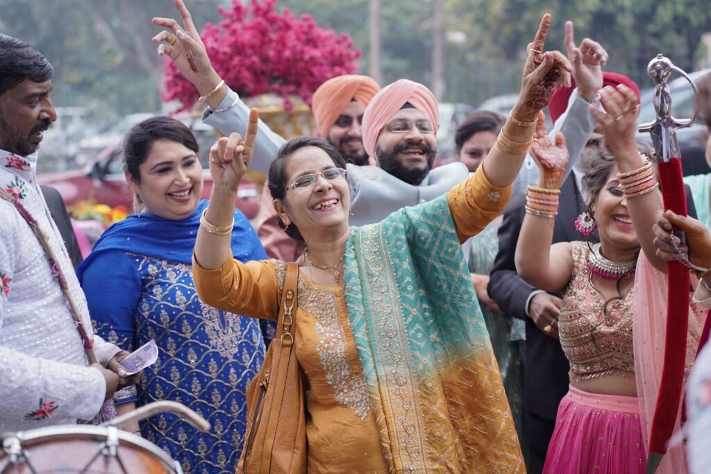 Group celebrating an Indian wedding ceremony with vibrant attire and joyful dancing.