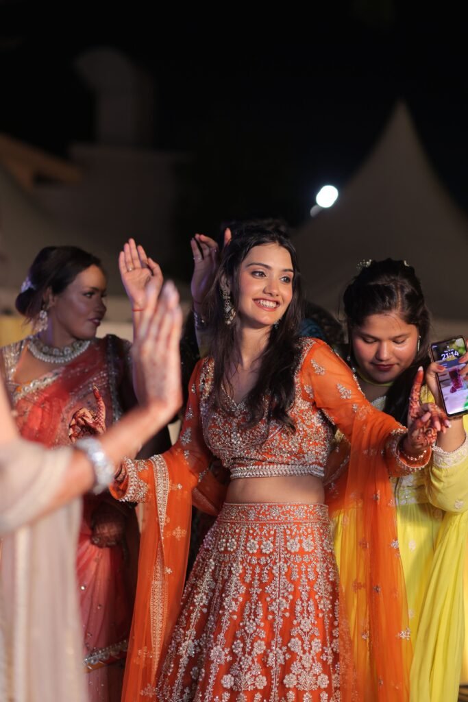 Adults joyfully dance in traditional Indian attire at a lively wedding celebration.