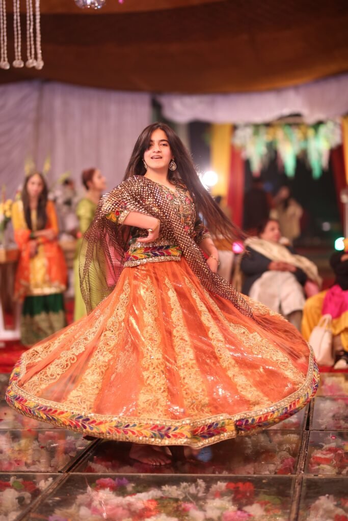 A woman in colorful traditional dress dances energetically at a festive celebration.